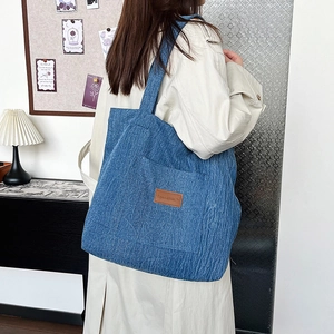 Large blue corduroy tote bag for work and study shown in a cozy interior setting