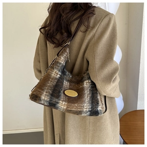 Detail view of brown and white checkered plush shoulder bag with elegant metal brand plate