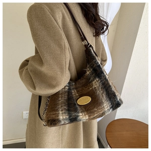 Detail of plush brown plaid shoulder bag with golden metal plate and chain strap