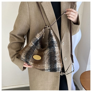 Detail of checkered woolen crossbody bag featuring a golden metal logo and chain strap