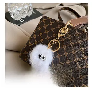 Gros plan d'un pompon blanc duveteux avec yeux de dessin animé sur un sac à main
