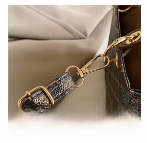 Macro shot of gold-plated metal clasp and kangaroo monogram pattern on brown handbag