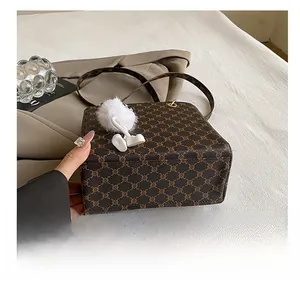 Close-up of durable base on dark brown monogram crossbody bag with plush charm