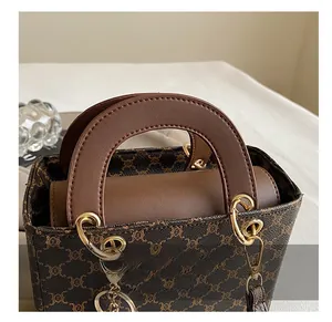 Detailed view of brown monogram canvas handbag with leather handle and gold hardware