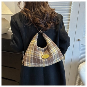 Detail of vintage plaid shoulder bag with gold logo on black wool coat for women