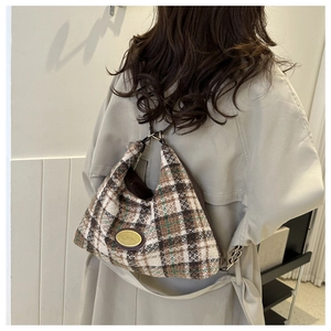 Detail of checkered tote bag with gold logo emblem on textured tweed fabric material