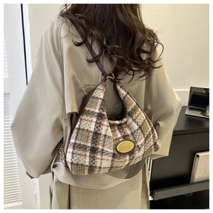 Detail of tweed checkered tote bag featuring gold nameplate and leather chain strap