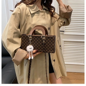 Vue détaillée du sac à main monogramme marron avec breloque peluche sur trench kaki
