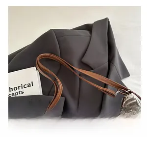 Detail of vintage brown plaid canvas bag featuring leather strap and metal chain