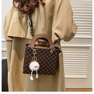 Detail of retro monogram crossbody bag with golden hardware and white plush monster charm