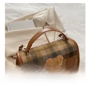 Detail of checkered fabric and plush bear patch on the vintage academic style handbag