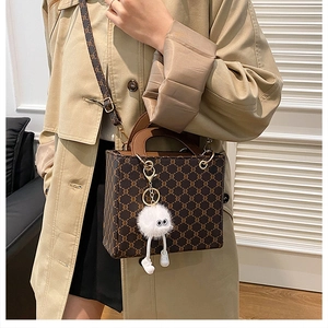 Detail of vintage tote bag featuring brown monogram canvas and cute plush doll charm