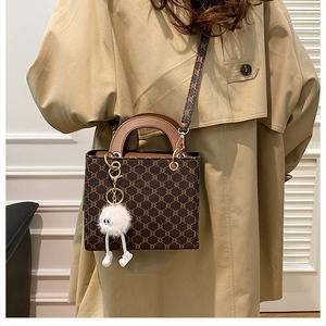 Detailed view of vintage monogram tote bag with brown leather handles and plush charm