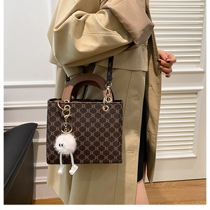 Fashionable dark brown vintage tote bag with plush monster charm on trench coat model