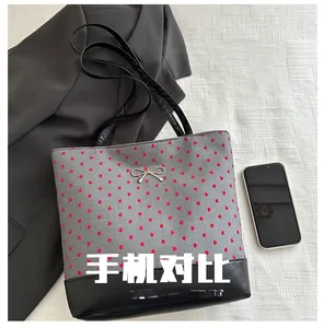 Detail of grey tote bag with red hearts, leather base and silver bow pendant decoration
