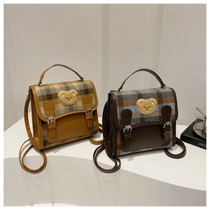 Detail of British style plaid handbags with plush bear patches and dual buckle closure