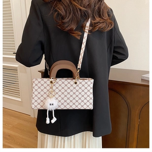 Détail d'un sac à main en similicuir avec motifs géométriques et charm en peluche en forme d'œil