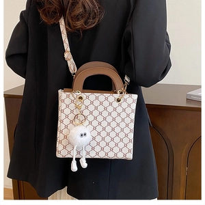 Detail of crossbody tote bag with monogram pattern and white plush monster charm