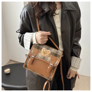 Detailed close-up of a vintage plaid backpack featuring a cute 3D teddy bear patch decoration