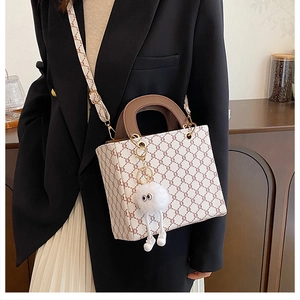 Detail of vintage patterned crossbody bag with plush charm on a black blazer outfit