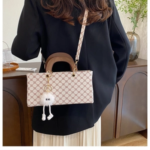 Détail d'un sac bandoulière vintage monogrammé avec un joli pendentif monstre en peluche