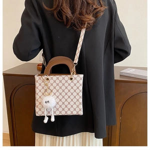 Detail of vintage beige shoulder bag with geometric patterns and plush doll charm