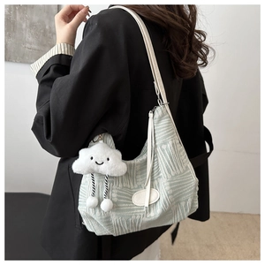 Detail of mint green textured canvas bag with a cute white cloud plush charm