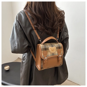 Detail of plaid backpack with teddy bear patch and leather straps in British style