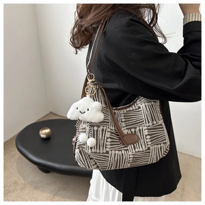 Detail of striped woven tote bag featuring a cute cloud charm and brown leather strap