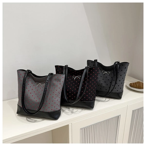 Detailed view of canvas tote bags with heart patterns and metal bow accents on white shelf