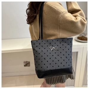 Close-up of gray polka dot canvas tote with silver bow metal detail and leather trim