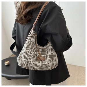 Detail of woven hobo bag with grey geometric patterns and brown leather strap on model