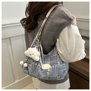 Detail view of plaid canvas bag with white plush cloud pendant and jacquard texture