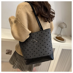 Detailed close-up of a large polka dot tote bag with a silver bow pendant on a model
