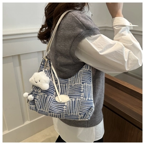 Detail of blue and white geometric fabric tote bag with plush cloud charm on leather strap