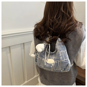 Detail of blue and white knit tote with geometric patterns and a cloud plush charm