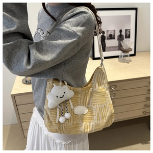 Detail of yellow checkered canvas shoulder bag with a plush cloud-shaped charm