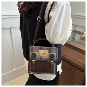 Close-up of British style plaid handbag with a 3D plush bear patch and leather straps