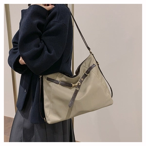 Close-up of khaki nylon tote bag with dark brown leather straps and golden metal hardware