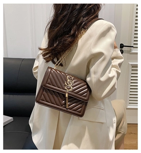 Detailed view of brown quilted crossbody bag with gold chain strap and fringe charm