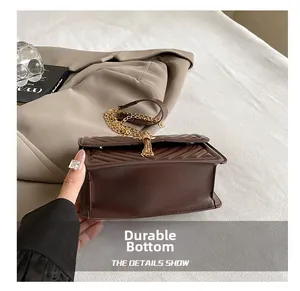 Macro shot of wear-resistant flat bottom on brown quilted crossbody bag with gold chain