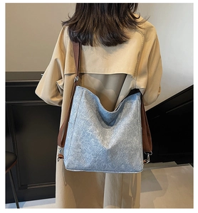 Detail of grey canvas tote bag with adjustable brown wide strap and silver metal hardware