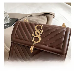 Detail of coffee brown quilted crossbody bag featuring golden letter lock and tassel