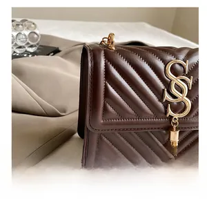 Detailed view of dark brown quilted leather bag with golden logo and tassel fringe