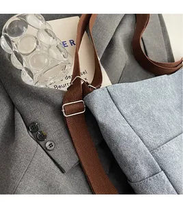 Close-up of adjustable woven shoulder strap and blue textured fabric on tote bag