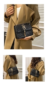 Detail showing the black quilted leather bag with gold V-stitch and metallic tassel