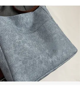 Close-up of textured grey-blue tote bag showing soft fabric and brown strap detail