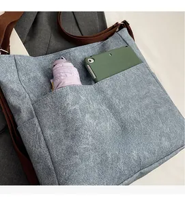 Detail of blue canvas tote bag front pocket storing a phone and purple umbrella