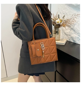 Detail of a brown quilted tote bag featuring an SS logo charm and a small coin purse