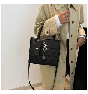 Dettaglio borsa a tracolla nera trapuntata con nappa dorata e mini pochette decorativa
